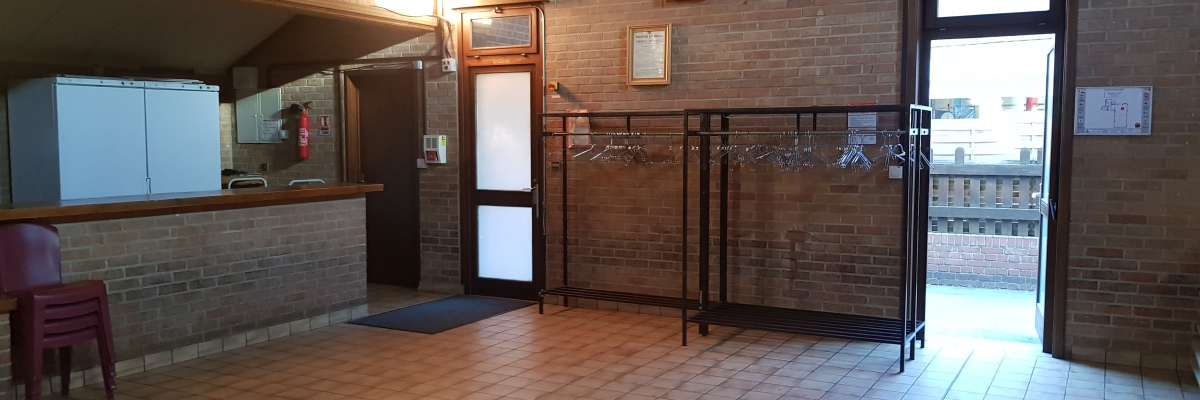 Réception avec comptoir, chaises, distributeur, frigo et porte.