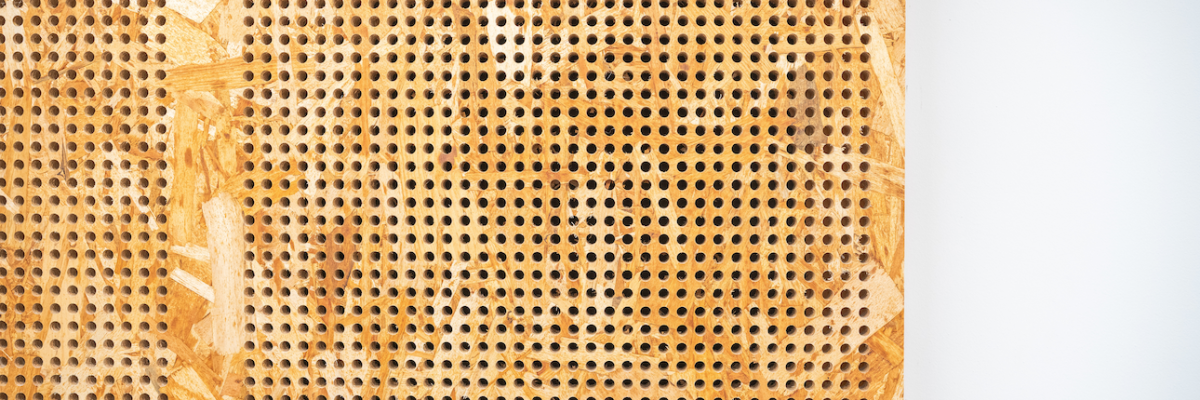 Panneau perforé en bois avec fond gris.