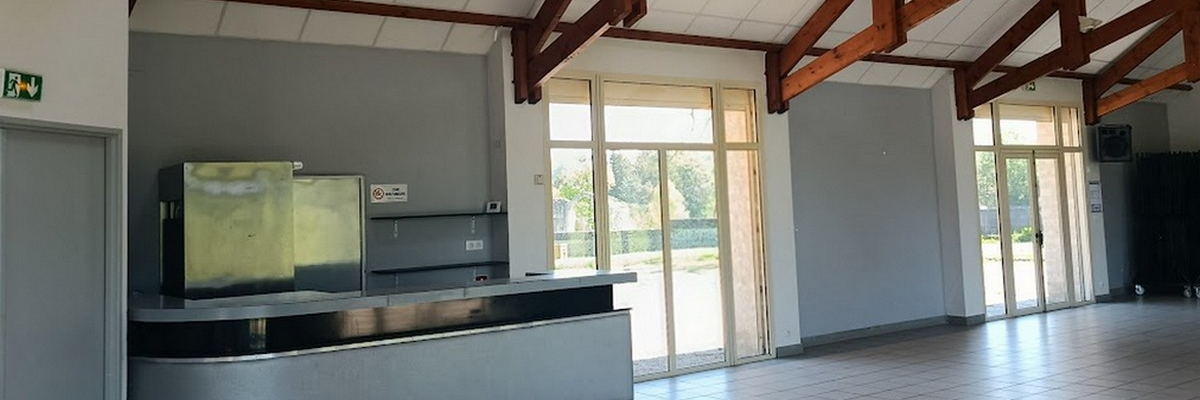 Salle avec comptoir, écran, portes vitrées et poubelle.