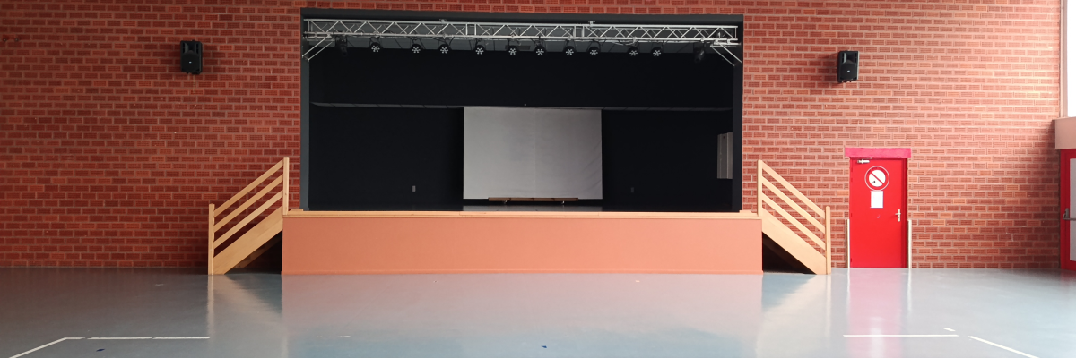 Salle avec scène, rideaux, rampes, haut-parleurs et extincteurs.