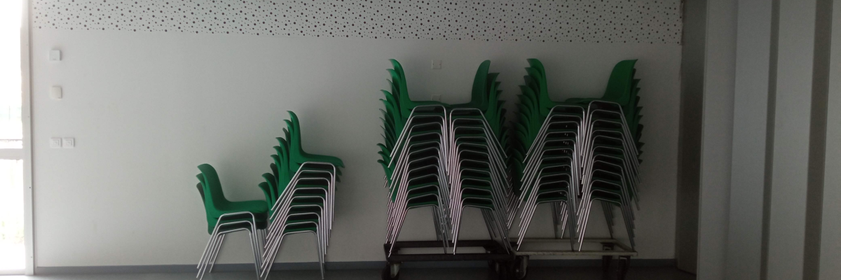 Chaises empilées sur un chariot et contre un mur.