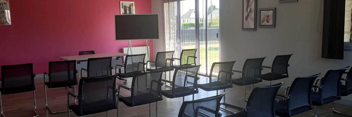 "Salle avec tables, chaises, écran, peintures murales et portes vitrées."