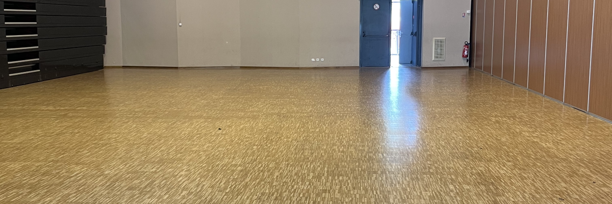 Salle vide avec sol en moquette, éclairage encastré, porte bleue et rangement sur le côté.