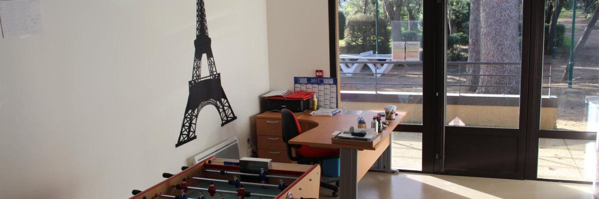 Pièce avec table de football, bureau, chaise, étagères et porte vitrée.