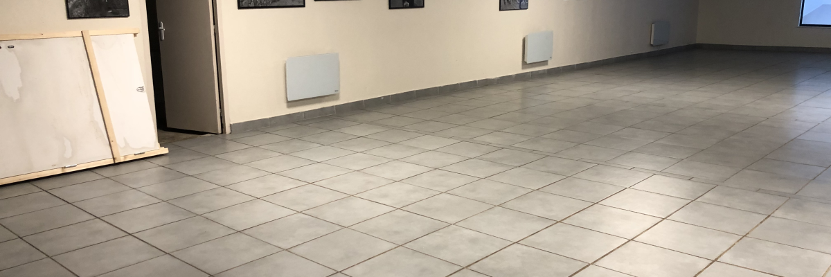 Salle vide avec photos, porte, radiateurs et écran.