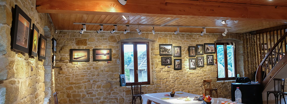 Pièce avec table, chaises, tableaux et escalier en colimaçon.
