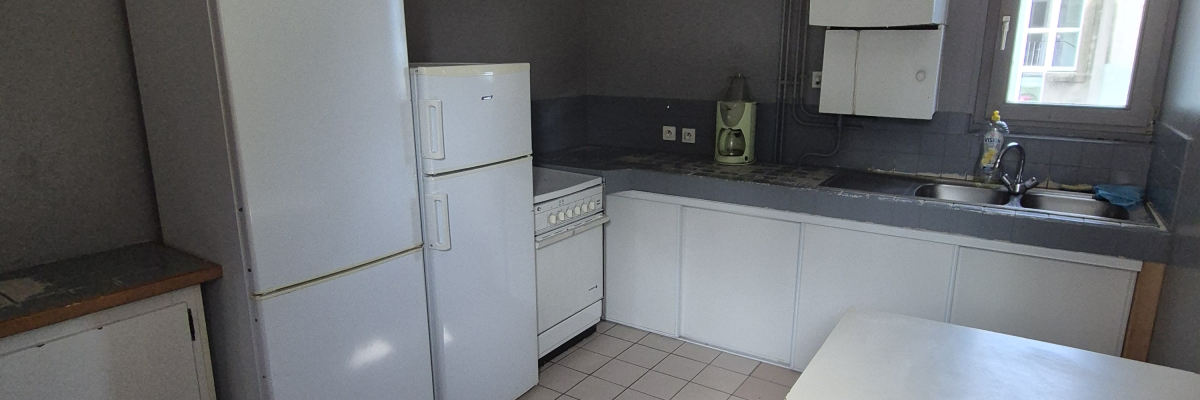 Cuisine avec réfrigérateur, congélateur, four, évier, table et chaises.