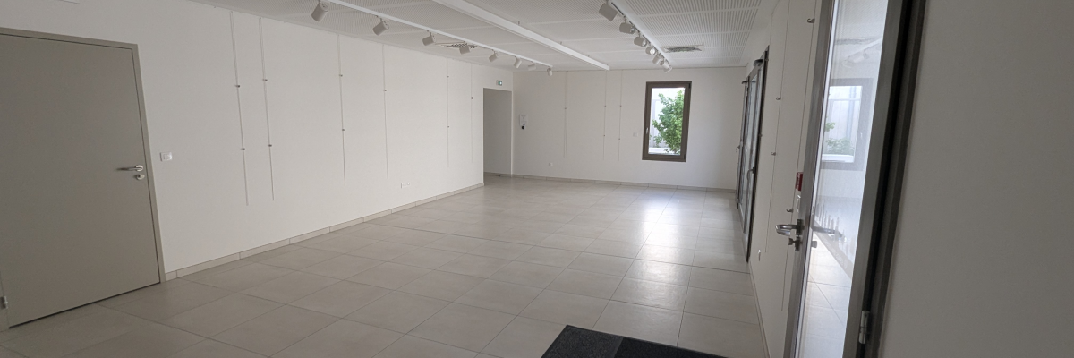 Salle vide avec porte, fenêtre, spots et tapis de sol.