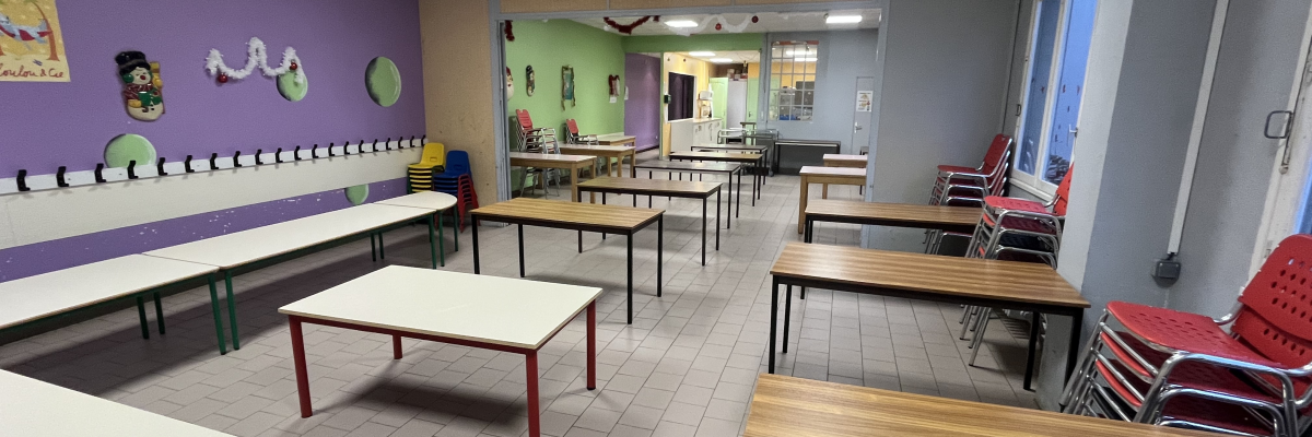 Salle avec tables, chaises, et bancs.