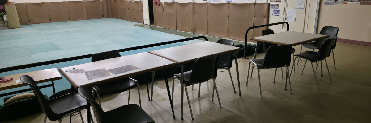 Grand espace avec tables, chaises, plateforme surélevée et panneaux d'affichage.