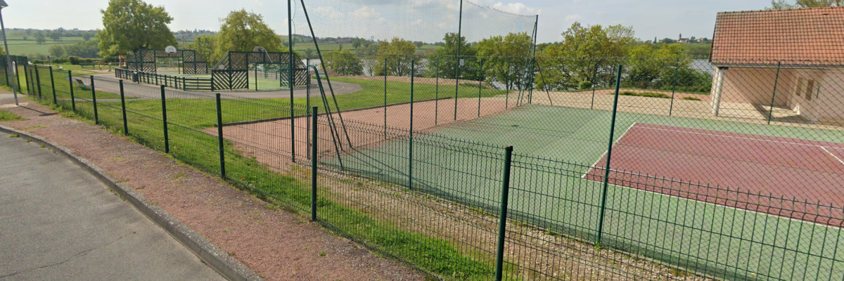 Tennis avec clôture, terrain, filet, bâtiment et route.