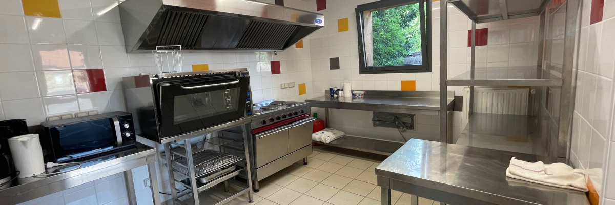 "Cuisine équipée avec plans de travail, hottes, écran, étagères et équipements de cuisine."