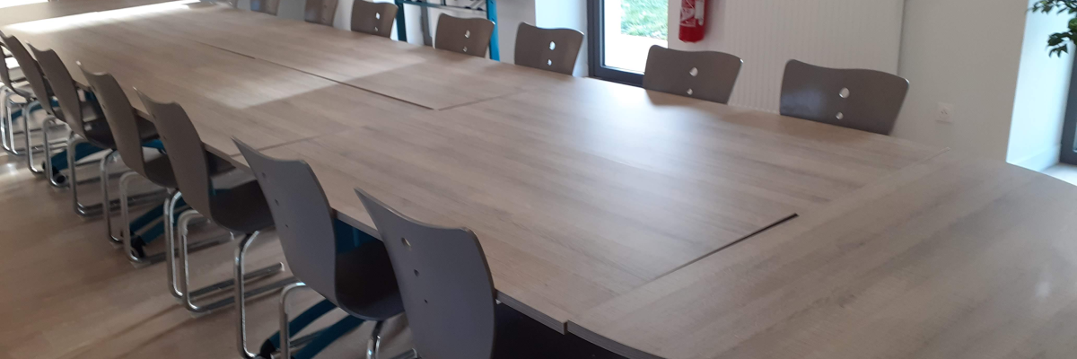 Grande table, chaises, radiateur, extincteur.