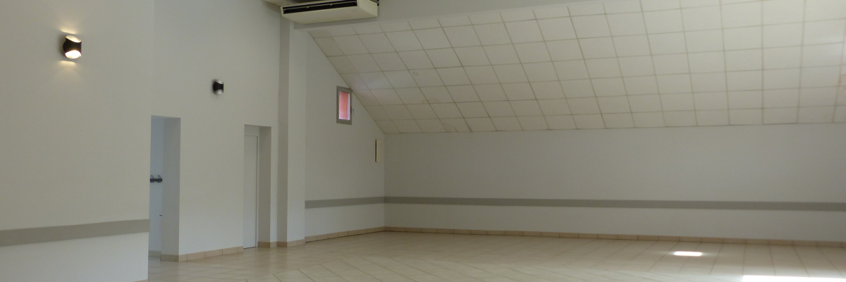 Salle vide avec éclairage, climatisation, porte et sortie de secours.