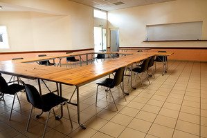 Pièce avec tables, chaises et tableau blanc.