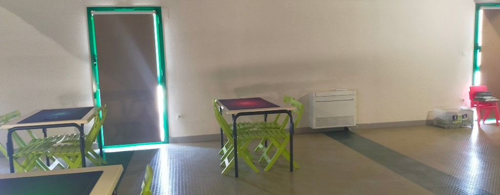 Salle avec tables, chaises, climatiseur et portes.