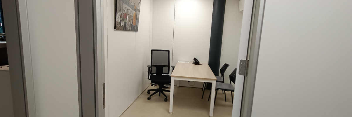 Petite salle de réunion avec table, chaises, téléphone et tableau.