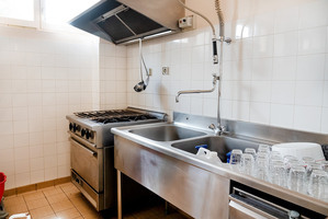 Cuisine avec évier, robinet, plaques de cuisson, hotte, et lave-vaisselle.