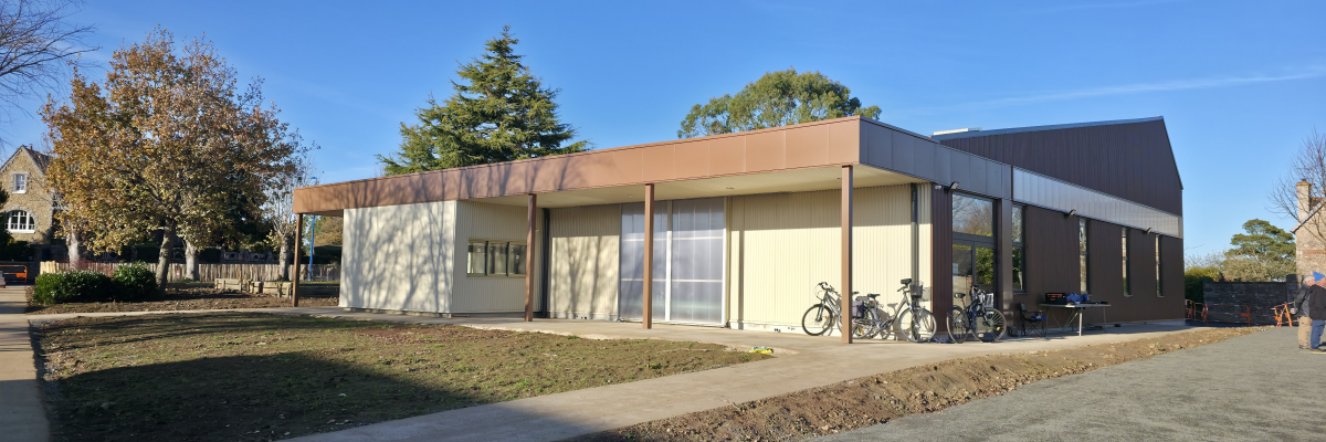 Bâtiment moderne avec toit plat, murs en béton, grandes fenêtres et vélos garés devant.