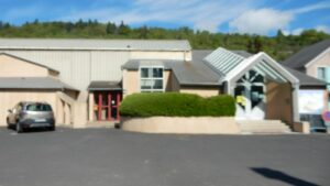 Bâtiment avec voiture garée, entrée principale et porte de garage.