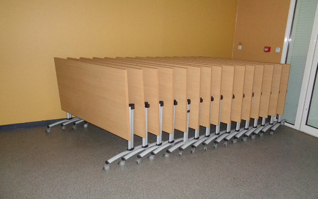 Bancs empilés sur roues dans une salle vide.