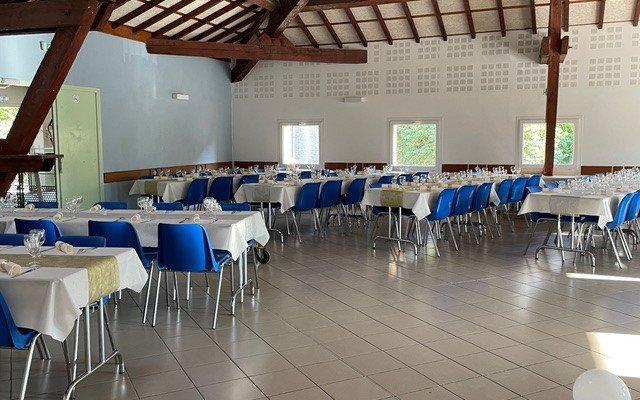 Salle avec tables, chaises, nappes, couverts.