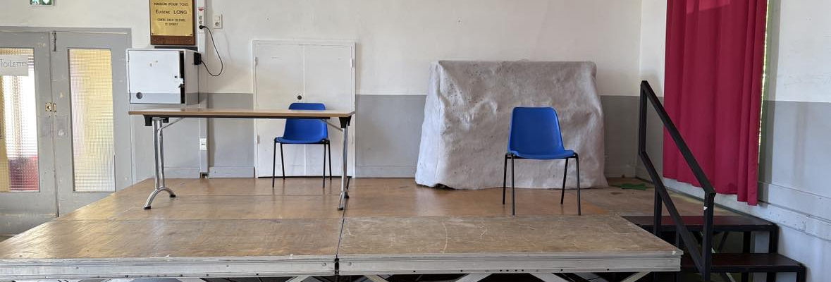 Salle avec table, chaises, podium, canapé et rideau.