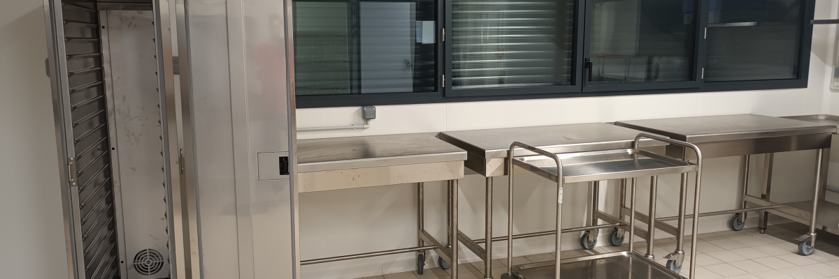 Cuisine avec chariots, four, évier et plans de travail.