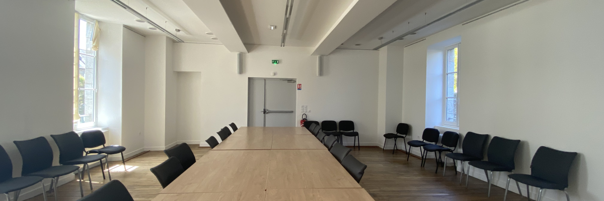 Salle de réunion avec table, chaises, et lumières.