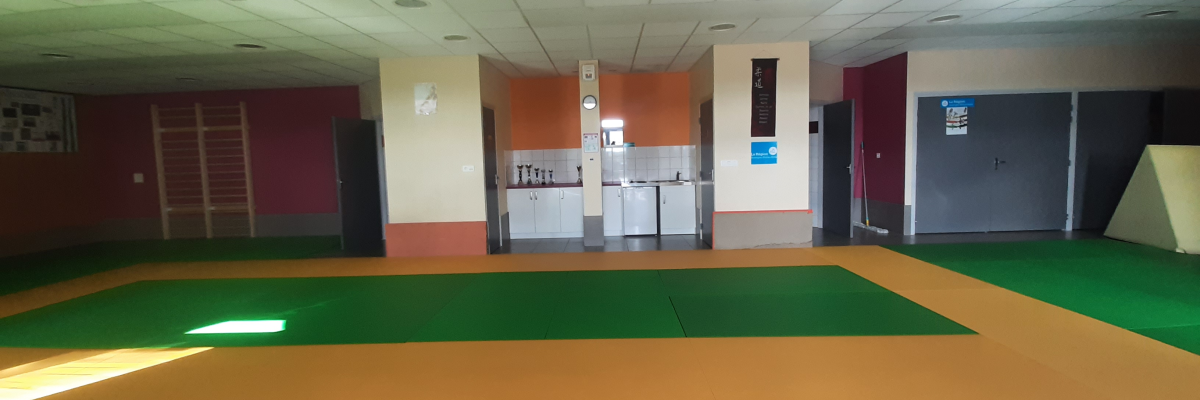 Salle avec sols colorés, évier, miroir, distributeur de savon et porte.