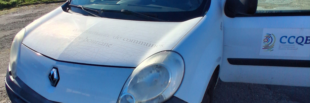 Camionnette blanche avec logo, plaque d'immatriculation visible.