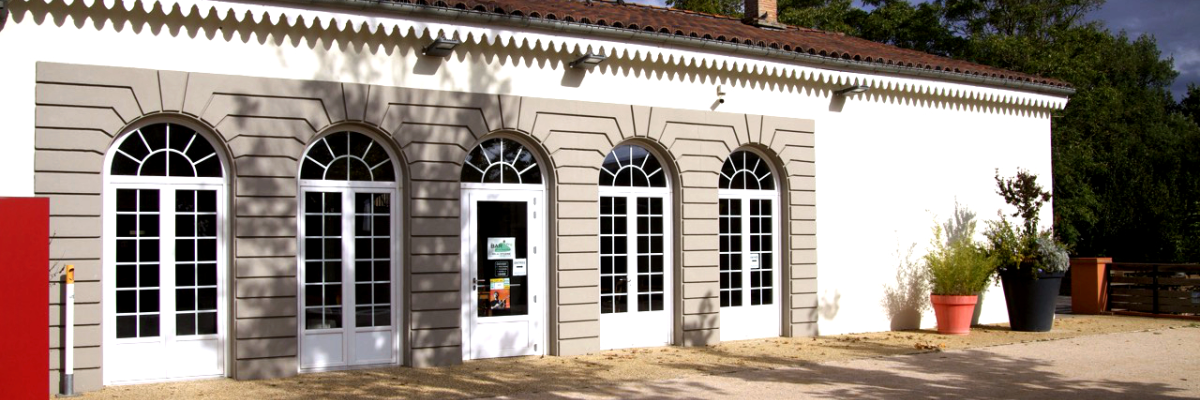 Bâtiment avec fenêtres, porte, pots de fleurs et banc.