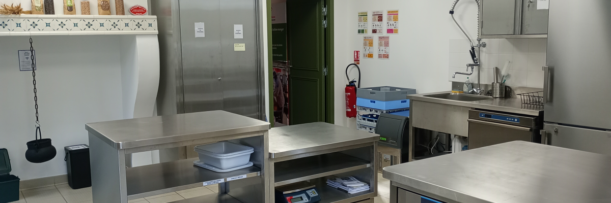 Cuisine avec plans de travail, étagères, réfrigérateurs, évier, équipement de cuisine, et extincteur.