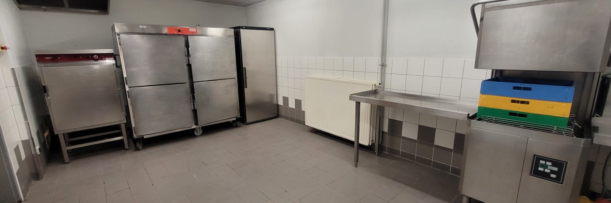 "Cuisine avec fours, congélateurs, étagères et plan de travail en inox."
