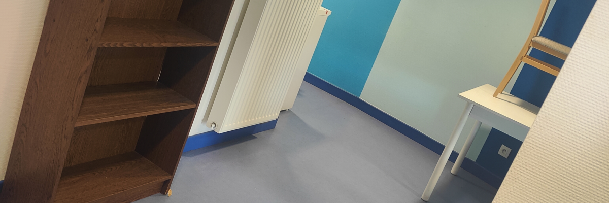 Bureau avec étagères, radiateur, table et chaises.