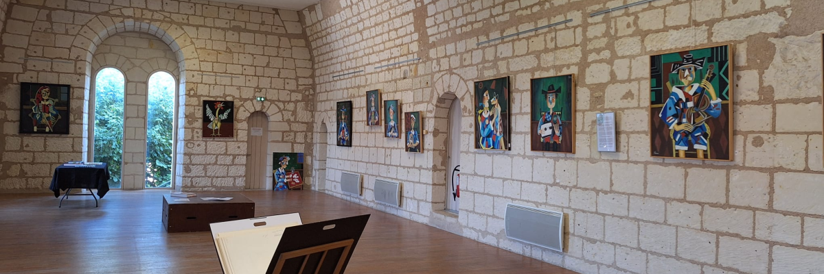 Salle d'exposition avec tableaux, cheminée, bancs, et fenêtre en arcade.