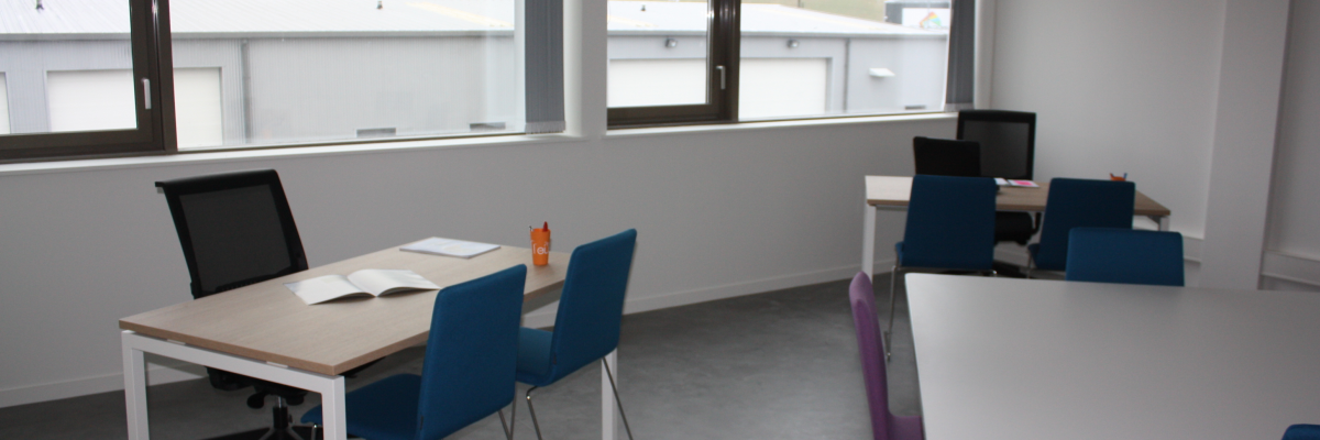 Salle avec table, chaises, ordinateurs, fenêtre.