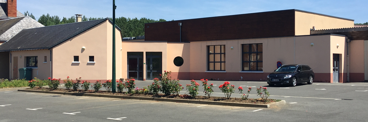 Bâtiment avec lampadaire, plantes et voiture.