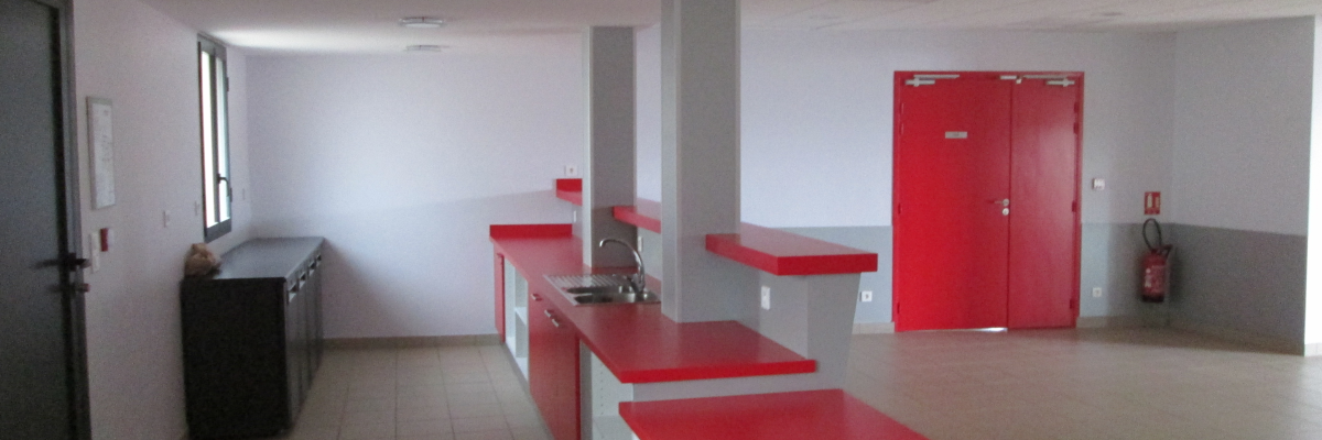 Cuisine avec plans de travail, évier, portes rouges et sols carrelés.