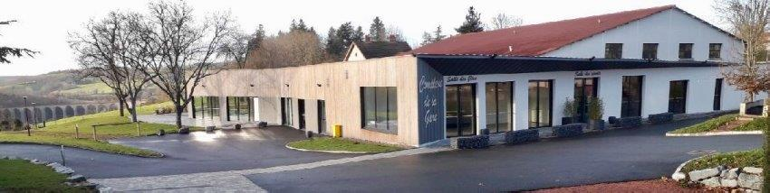 Bâtiment commercial avec fenêtres, portes, parking et végétation.