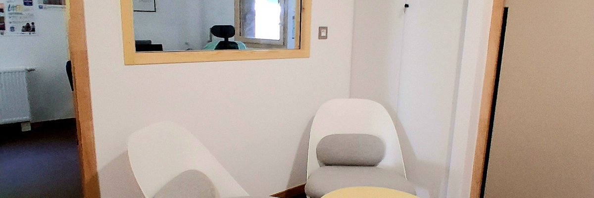 Petite pièce avec deux chaises, une table basse, miroir et porte.