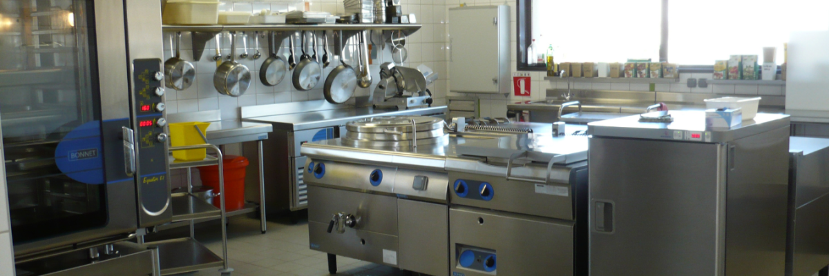 Cuisine équipée avec plaques de cuisson, étagères, poêles, évier, et divers ustensiles.