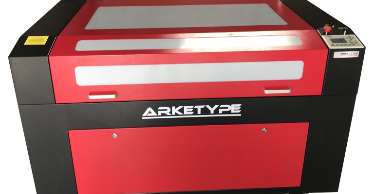 Machine à laser rouge avec plateau transparent et panneau de contrôle. Roues noires.