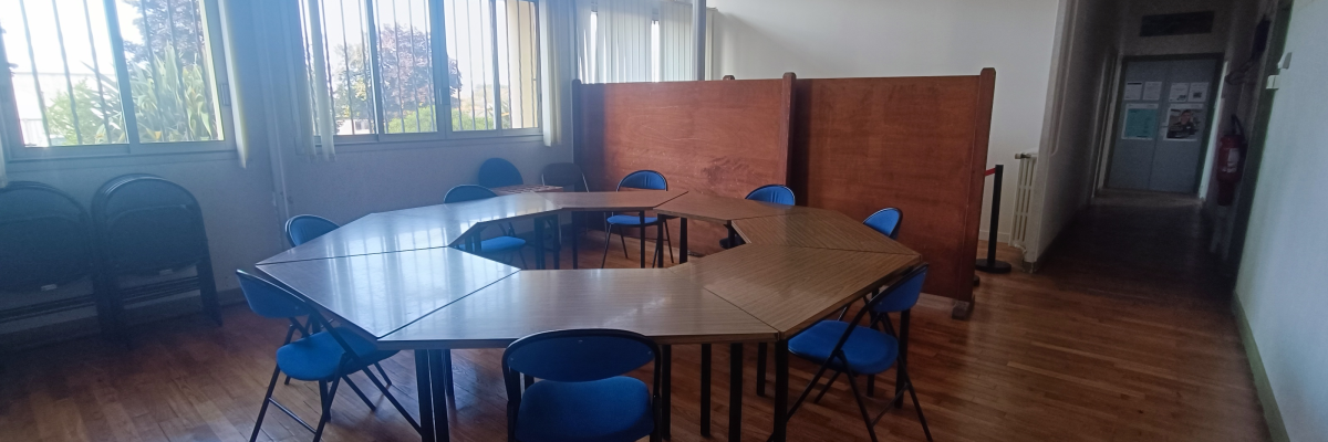 Salle de réunion avec table, chaises, paravents, radiateur.