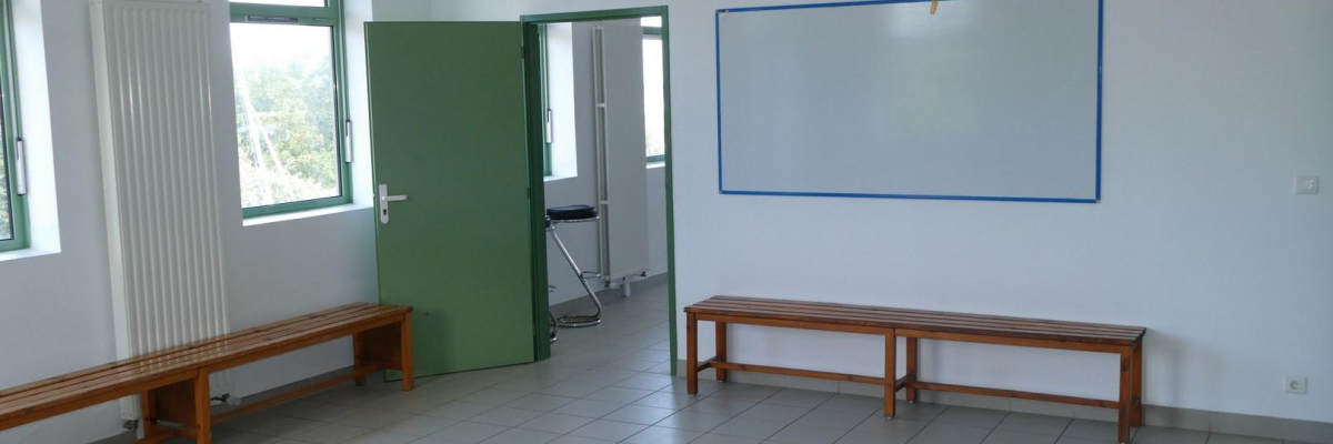 Salle avec bancs, tableau blanc et porte verte.