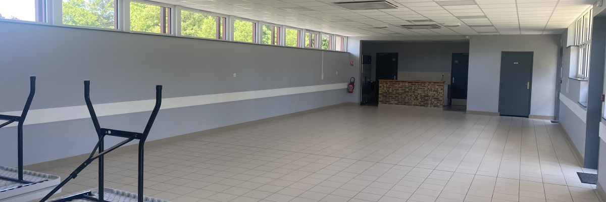 Salle vide, fenêtres, tables pliantes et portes.