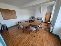 Salle avec table, chaises, tableau blanc, étagères et armoire.