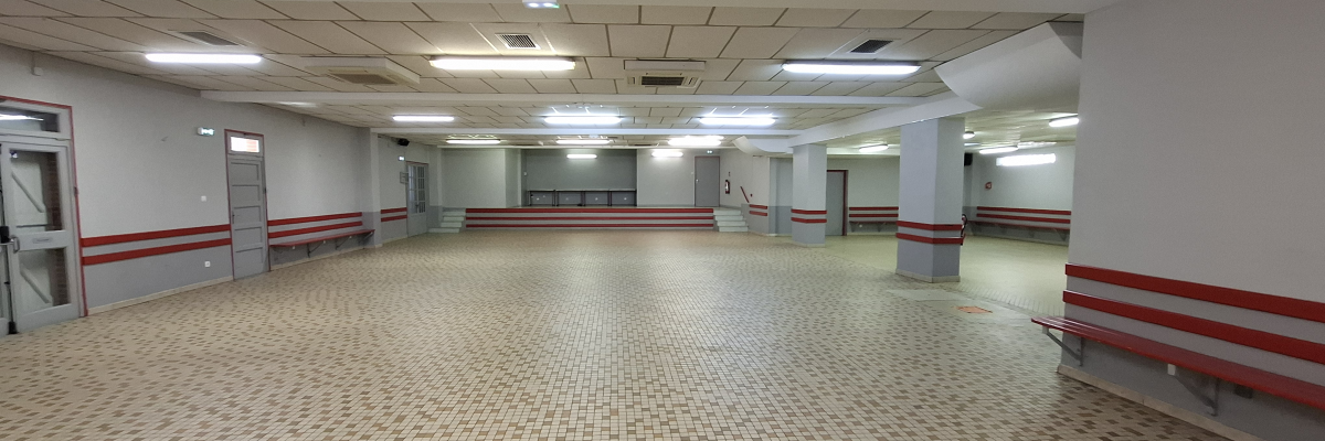 Salle vide avec bancs, portes et éclairage au plafond.