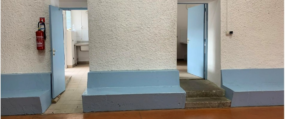 Salle avec bancs, portes, extincteur, et éclairage.