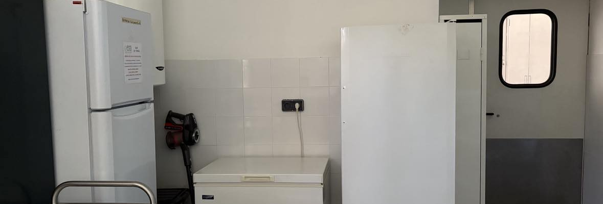 Cuisinette avec réfrigérateur, congélateur, plan de travail, évier et porte.